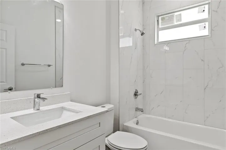 Full bathroom with vanity, tiled shower / bath, and toilet