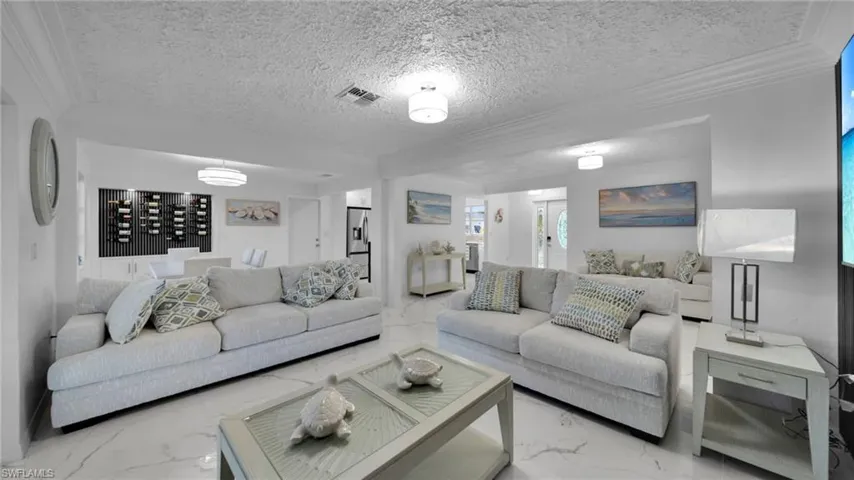 Living room featuring marble finish flooring, a textured ceiling, and crown molding