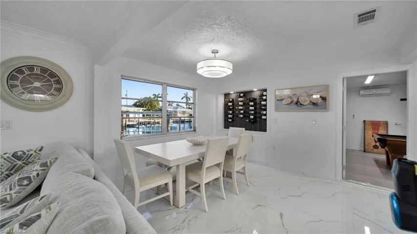 Dining space with light marble finish flooring, a textured ceiling, and a wall mounted AC