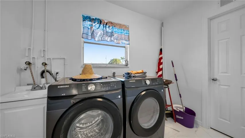 Laundry area with washer and clothes dryer and light marble finish floors