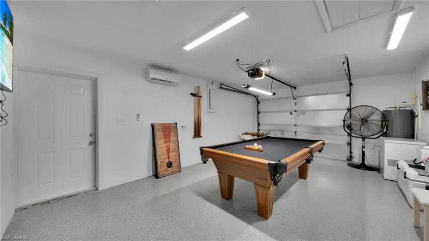 Playroom featuring billiards table, attic access, a wall unit AC, water heater, and a garage