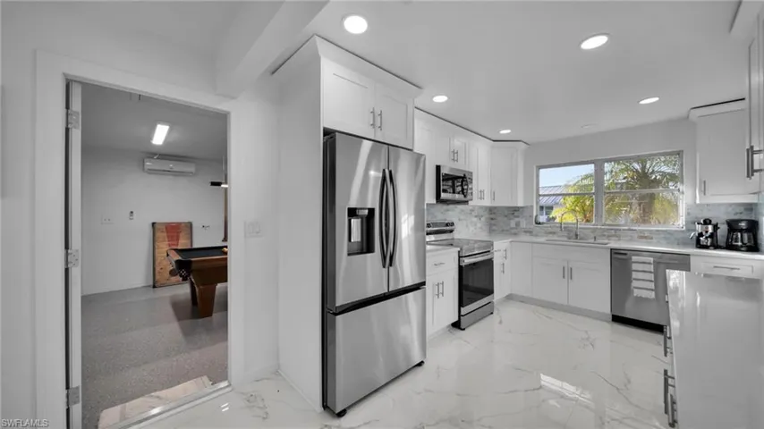 Kitchen featuring stainless steel appliances, light marble finish floors, white cabinetry, and recessed lighting