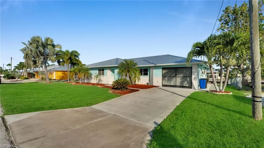 Ranch-style house featuring brick siding, concrete driveway, a metal roof, and a garage