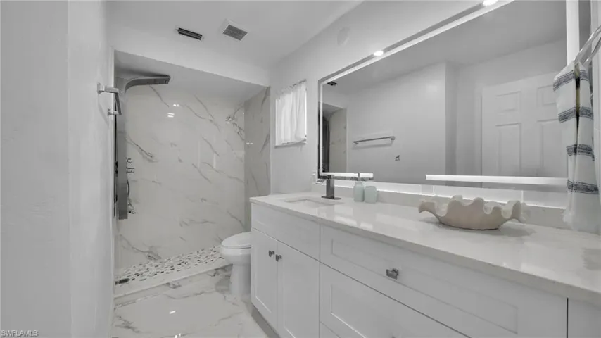 Bathroom featuring light marble finish floors, vanity, and a marble finish shower