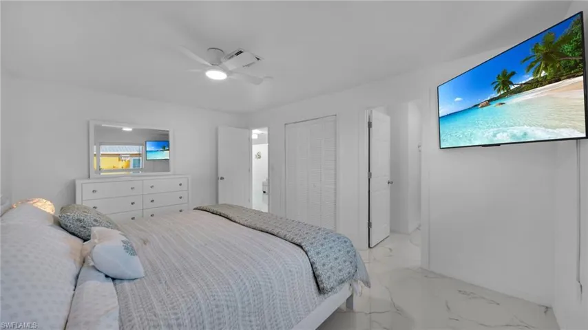 Bedroom featuring marble look tile flooring, ceiling fan, and a closet