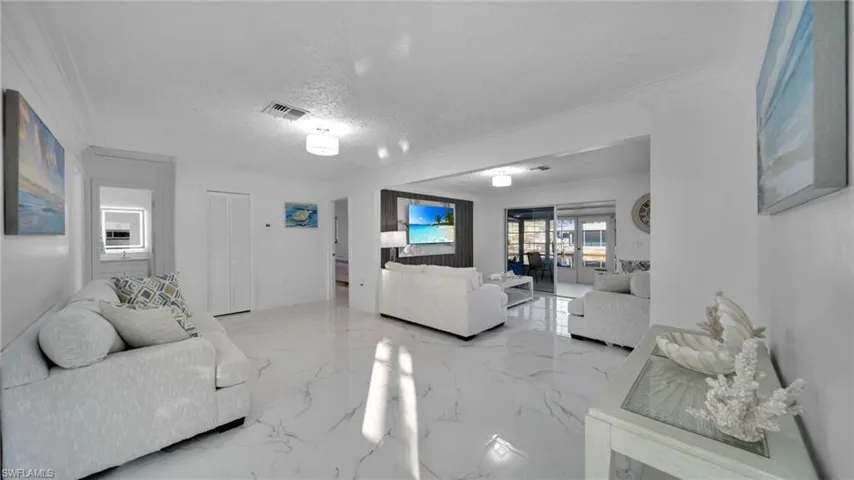Living area featuring light marble finish flooring, a textured ceiling, and crown molding