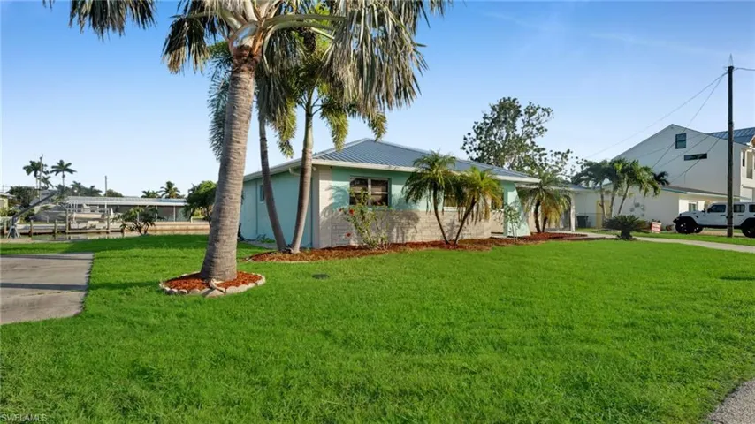 Ranch-style home featuring a front yard, concrete driveway, and a metal roof