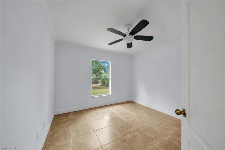 Room featuring ceramic tile flooring, a ceiling fan, a single window, white baseboards, and white walls