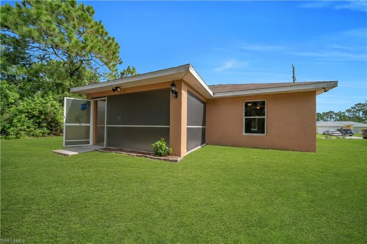 Exterior stucco finish with a screened patio featuring a double screen door entry