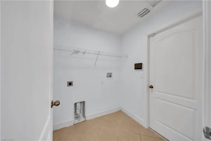 Dedicated utility space featuring tile flooring and white walls
