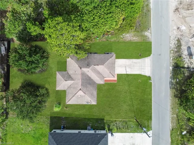 Aerial perspective of a single-story residence featuring a multi-gabled roof and a concrete driveway