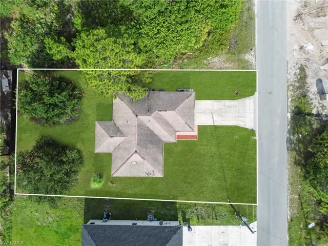 Aerial perspective showcasing a single-story residence with a multi-gabled roof and an attached concrete driveway