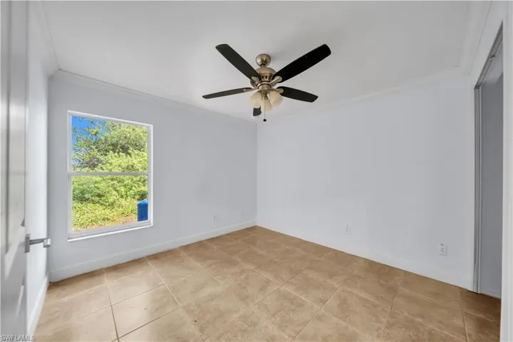 Interior room featuring a ceiling fan with integrated lighting, a single window, and neutral-toned tiled flooring