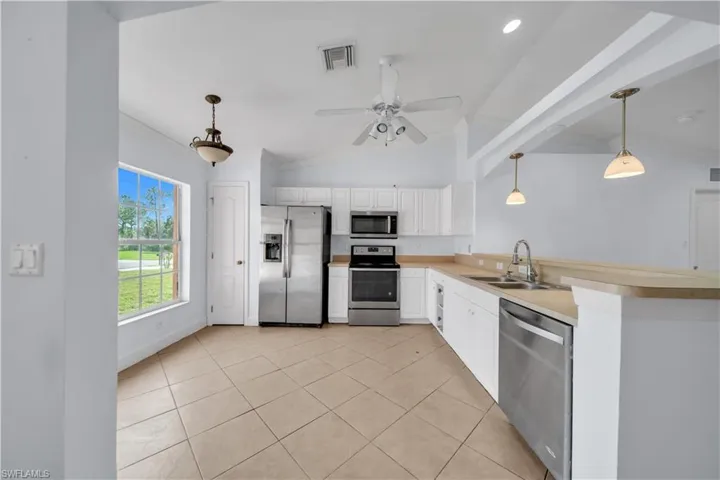 Kitchen featuring white cabinetry, stainless steel appliances, a breakfast bar, and tile flooring