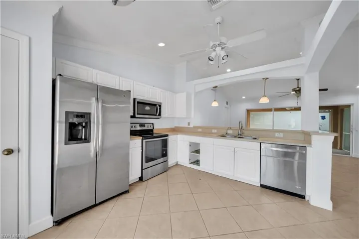 Kitchen featuring white cabinetry, tile flooring, stainless steel appliances, and a pass-through window