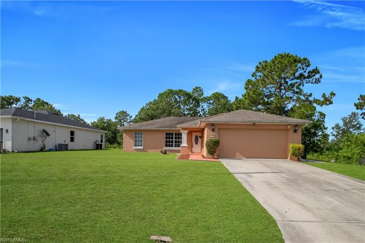 Single-story residence featuring a two-car garage, expansive front lawn, paved driveway, covered entry, and a stucco exterior finish