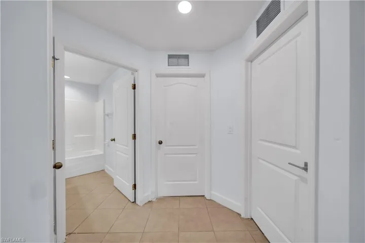 Hallway featuring tile flooring, white interior doors, and recessed lighting
