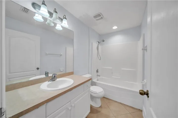 Bathroom featuring a vanity with a white cabinet base, a drop-in sink, and a light-colored countertop