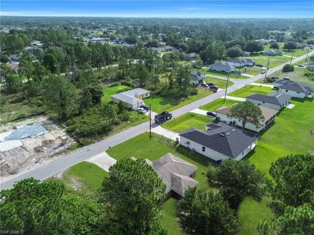 Aerial perspective showcasing a residential street with single-story homes and undeveloped lots