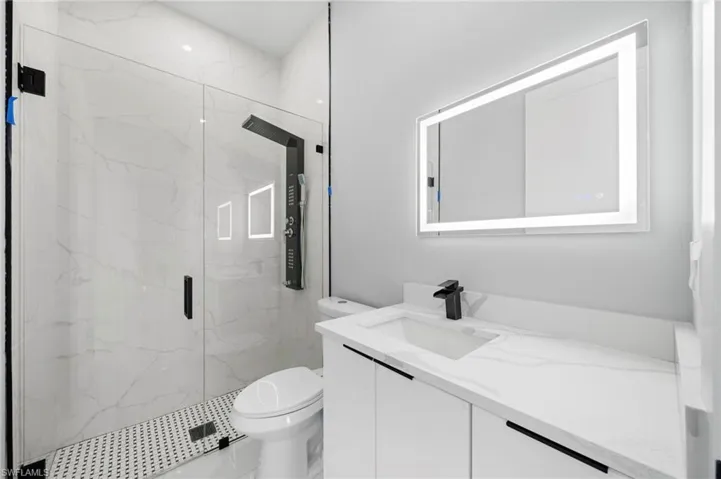 Bathroom featuring an enclosed shower, vanity, and toilet