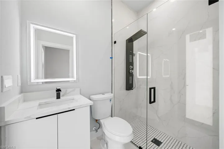 Bathroom with a shower with door, toilet, and vanity