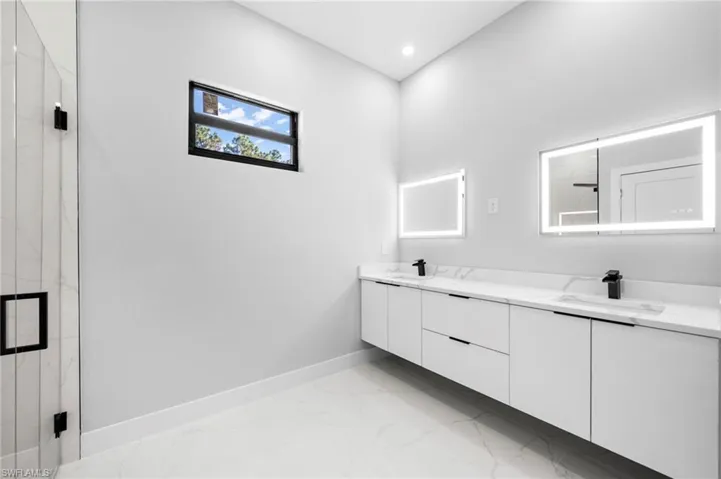 Bathroom with tile floors, large vanity, double sink, and plenty of natural light