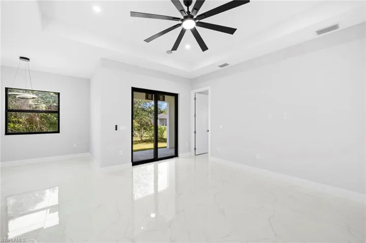 Tiled empty room featuring ceiling fan and a raised ceiling