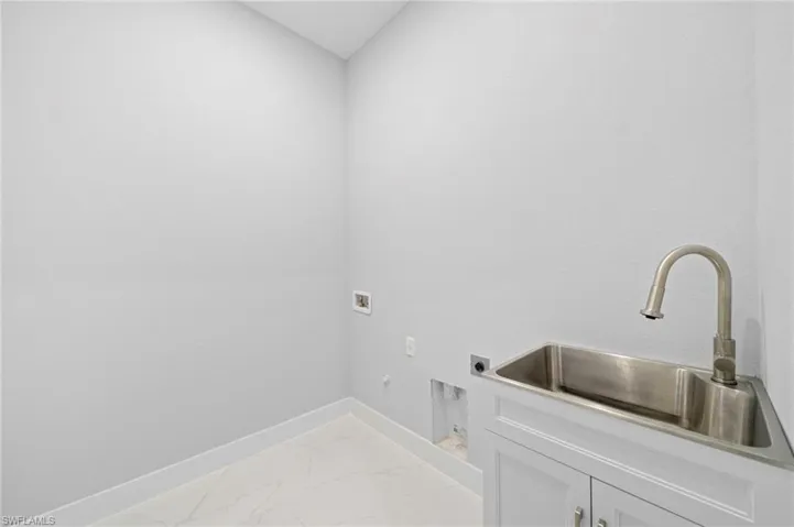 Laundry area featuring cabinets, electric dryer hookup, hookup for a gas dryer, sink, and light tile flooring