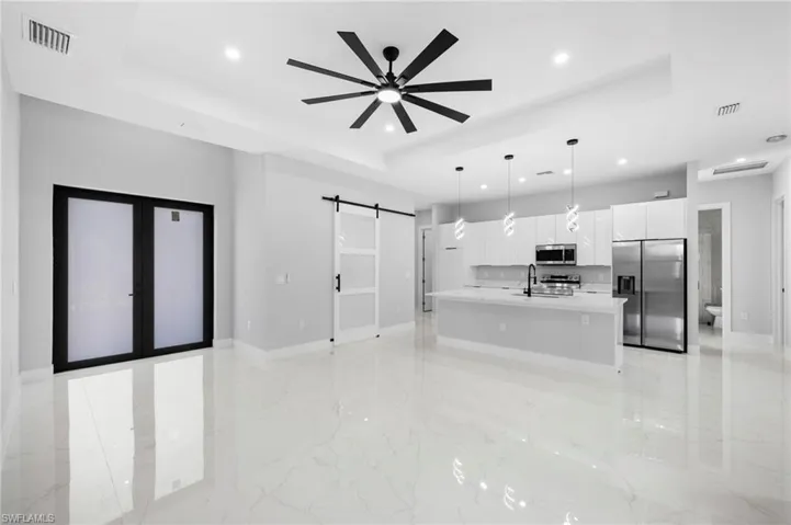 Kitchen featuring appliances with stainless steel finishes, a tray ceiling, a barn door, and a center island with sink