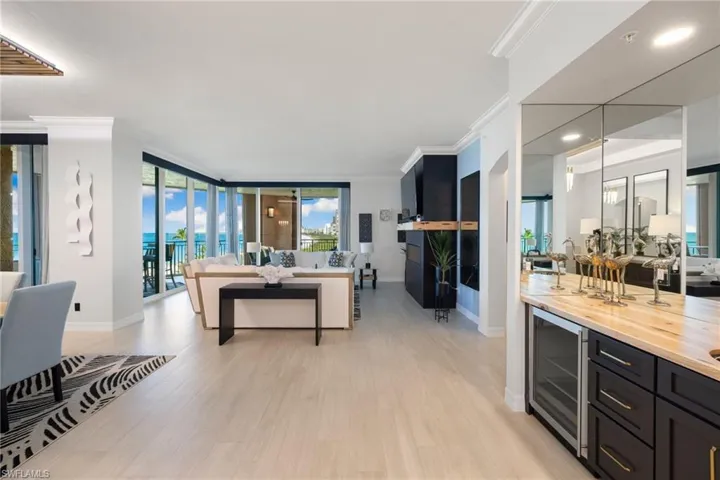 Family room with wine cooler, crown molding, floor to ceiling windows, and light wood-type flooring