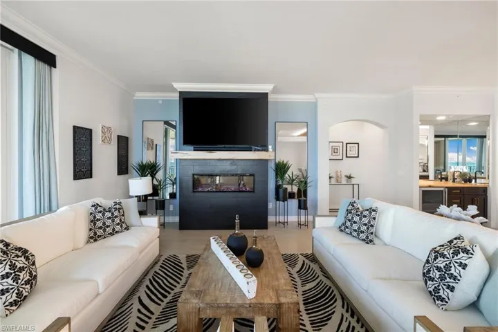 Family room with sink, wine cooler, ornamental molding, a tiled fireplace, and hardwood / wood-style flooring