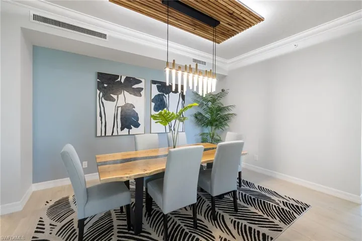 Dining space featuring ornamental molding, light hardwood / wood-style floors, and a notable chandelier