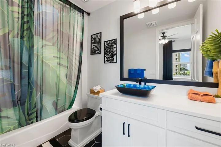 Full bathroom with shower / bath combo, tile patterned floors, vanity, ceiling fan, and toilet