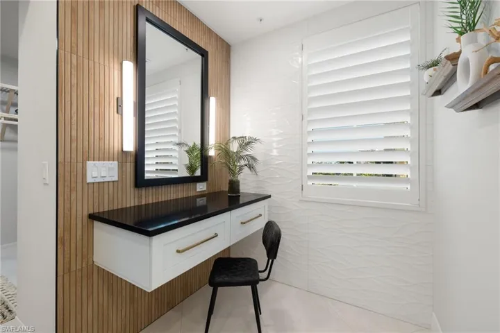Vanity sitting area featuring light tile patterned flooring and tile walls