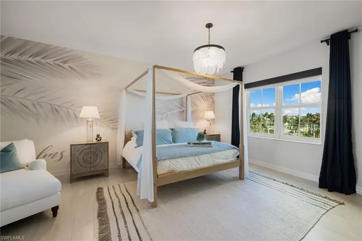 Primary bedroom with light hardwood / wood-style floors and a notable chandelier