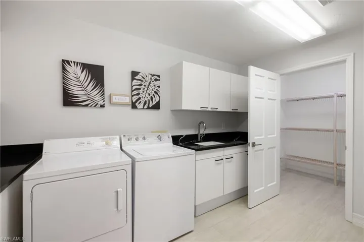 Clothes washing area featuring washer and dryer, sink, and cabinets