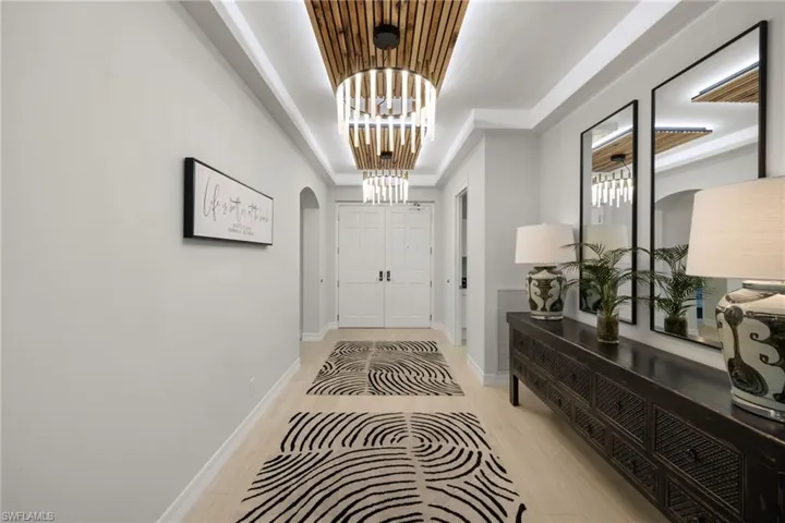 Foyer entrance with a notable chandelier, light hardwood / wood-style flooring, and a tray ceiling