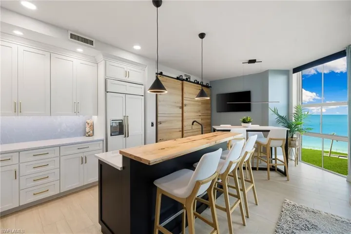 Kitchen with white cabinetry, paneled built in refrigerator, pendant lighting, a breakfast bar area, and a kitchen island