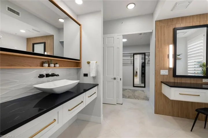 Primary bathroom with tile patterned floors, vanity, and tasteful backsplash