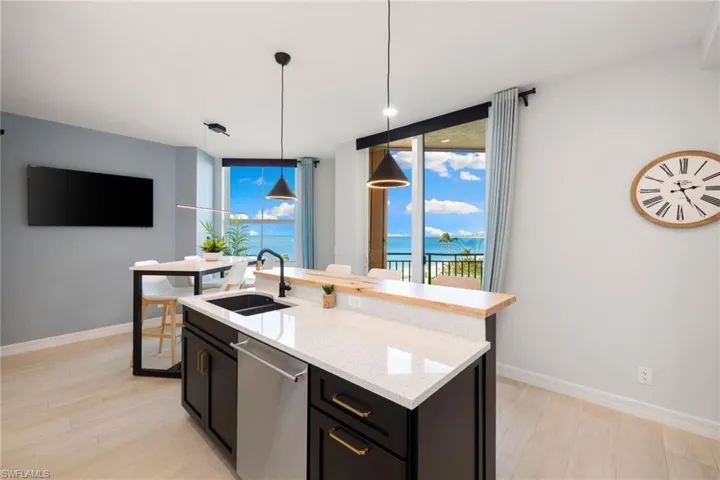 Kitchen featuring light wood-type flooring, sink, decorative light fixtures, a water view, and dishwasher