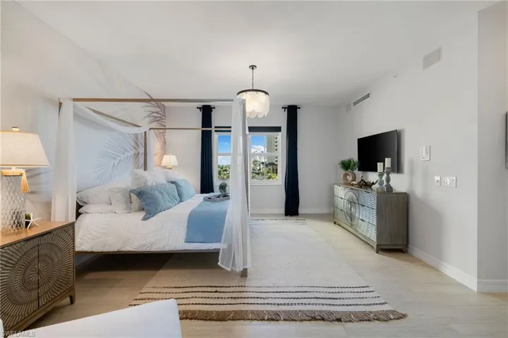 Primary bedroom with light hardwood / wood-style floors and a notable chandelier