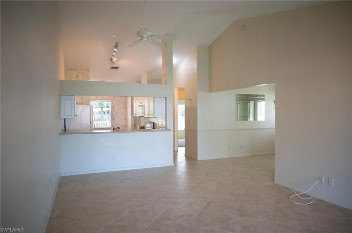 Unfurnished living room with a ceiling fan, lofted ceiling, and light tile patterned floors