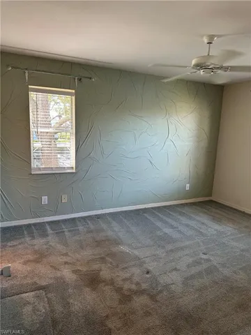 carpet floors, a textured feaure wall, and ceiling fan, two windows for natural light