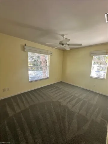 Second bedroom featuring carpet, full closet, two windows and a ceiling fan