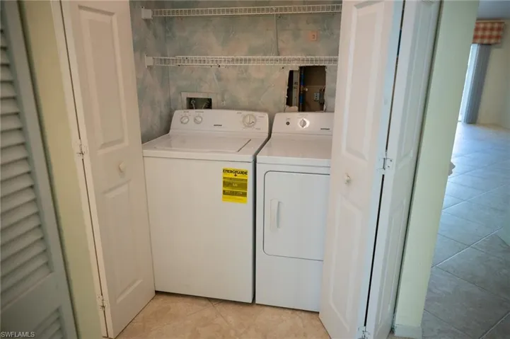 In unit Laundry area with light tile patterned floors and washer and dryer