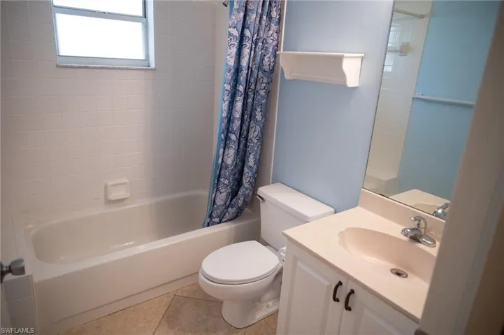 Full bath with vanity, shower / tub combo, and light tile patterned floors