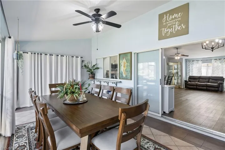 Dining area with lofted ceiling, ceiling fan with notable chandelier, and hardwood / wood-style floors