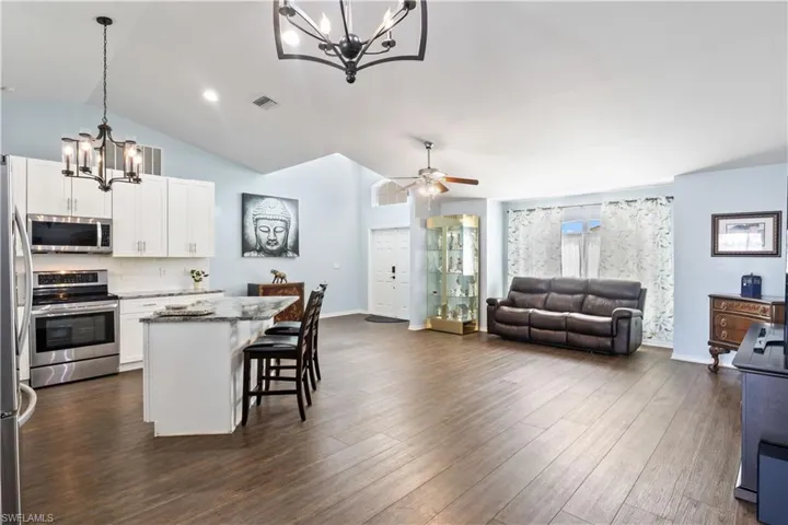 Kitchen featuring white cabinetry, appliances with stainless steel finishes, vaulted ceiling, and hanging light fixtures