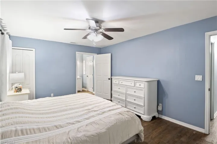 Bedroom with dark wood-type flooring, ceiling fan, and a closet