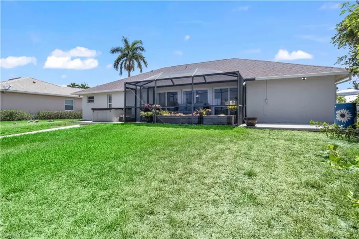 Rear view of house with a yard, a patio area, and glass enclosure
